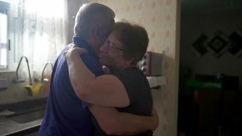 Romantic Scene of Elderly Couple Dancing by Kitchen Window, Senior Husband .. Stock Photos