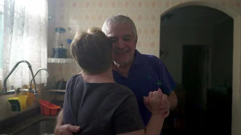 Romantic Scene of Elderly Couple Dancing by Kitchen Window, Senior Husband .. Stock Photos
