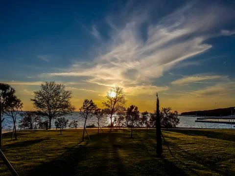 Romantic sunset by a beach. The sun sets over the horizon. The sunbeams refle Stock Photos