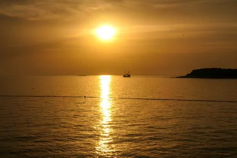 Romantic sunset by a beach. The sun sets over the horizon. The sun beams refl Stock Photos