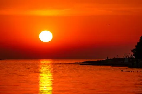 Romantic sunset by a beach. The sun sets over the horizon. The sun beams refl Stock Photos