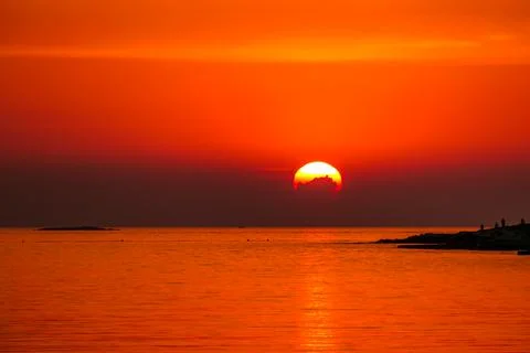 Romantic sunset by a beach. The sun sets over the horizon. The sun beams refl Stock Photos