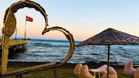 Romantic Sunset Scene with Turkish Flag and Heart-Shaped Arch on the Beach Stock Footage 322829123