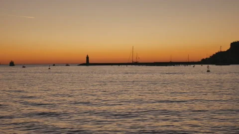 A romantic sunset with the silhouette of a lighthouse in the distance. Stock Footage 155169617