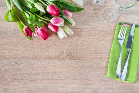 Romantic table setting with bunch of fresh tulips and fork and knife on green Stock Photos