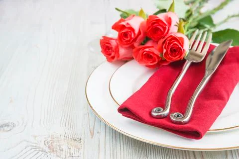Romantic table setting. Forged fork and knife on red napkin and white plates  Stock-Fotos