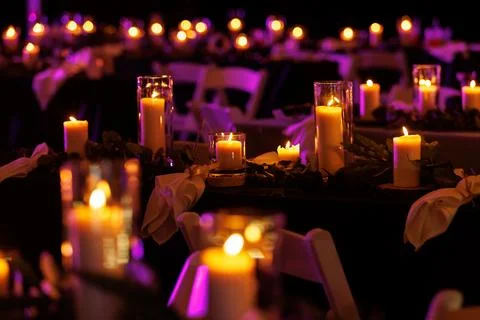 A romantic table setting with lit candles and greenery at a nighttime event. Foto stock