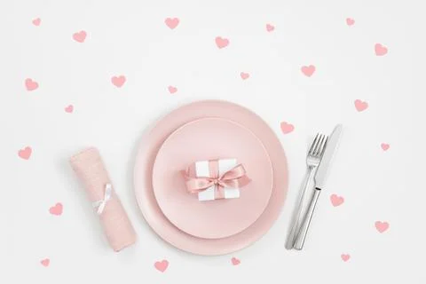 Romantic table setting with pink plate, gift and confetti hearts Stock Photos