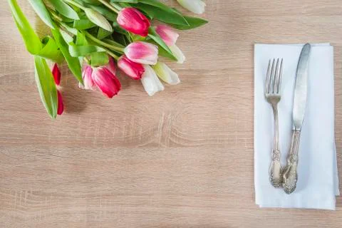 Romantic table setting. Vintage fork and knife on white napkin and bunch of p Stock Photos