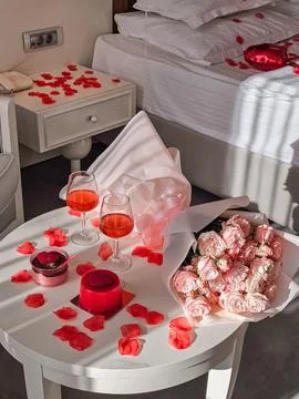 Romantic Table with Two Glasses and Desserts Near Decorated Bed Stock Photos