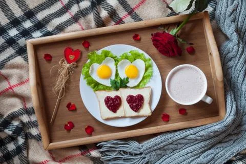Romantic valentines day breakfast in bed with heart-shaped eggs, toasts, jam Stock Photos