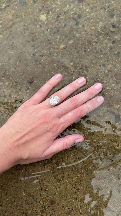 Romantic vertical video of hand with oval diamond ring by the shore Video stock 316769962