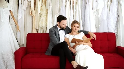 Romantic wedding couple sitting on sofa. Looking at book together. Stock Footage 99013690