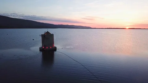 A romantic windmill on a sea lagoon at sunset Aerial view Stock Footage 107847843