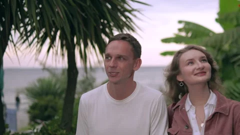 Romantic young couple in 30s talking and walking along a tropical seaside at Stock Footage 320529879