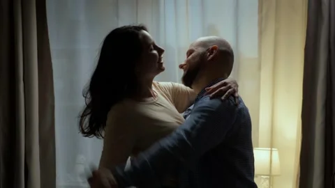 A romantic young couple dancing in front of a window holding hands 스톡 동영상 242600104