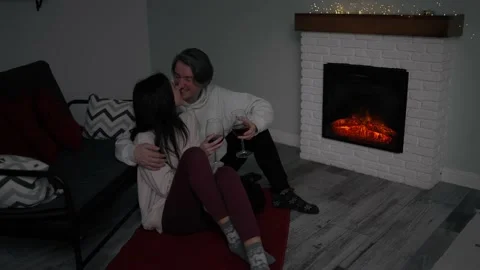 Romantic young couple drinking red wine next to the fireplace Stock Footage 234960399