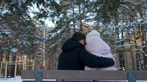 Romantic young couple hugging on park bench in snowy winter forest 库存影片 330106397