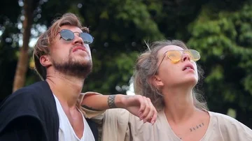 Romantic young couple is talking to each other and looking in the sky outdoor. Video stock 85526433