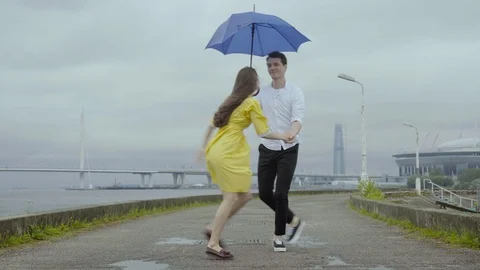 Romantically couple dancing twist on the rain at the embankment in th city Stock Footage 80198345