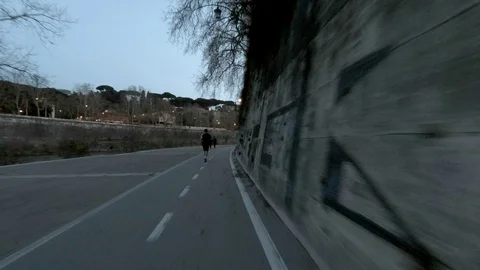 Rome, Moving view along Tiber River at dusk with a man doing jog Stock Footage 104402060