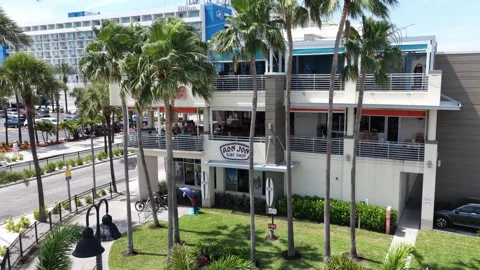 Ron Jon Surf Shop sign marks white building framed by tall palm trees in Stock Footage 340192053