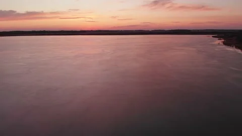 Rone flying just above the ice on a recently frozen lake at sunset Stock Footage 142809206