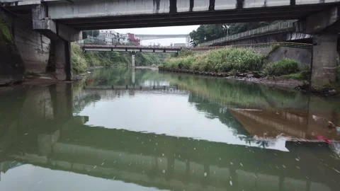 Rone shot flying under bridge and over reflective water (Taiwan) Stockbeeldmateriaal 329052295