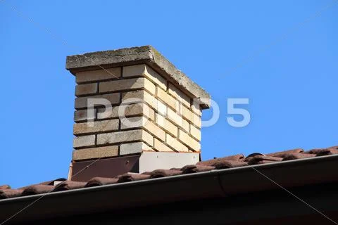 Roof Detail Of A Detached House With Red Roof Tile And Beige Chimney Against
