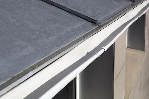 Roof gutter made of stainless sheets rainwater drainage pipe close-up. Stock Photos