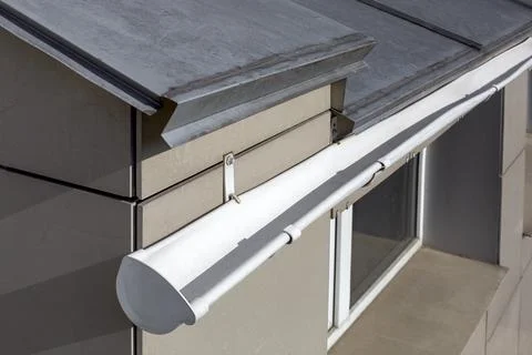 Roof gutter made of stainless sheets of white color rainwater drainage pipe. Stock Photos