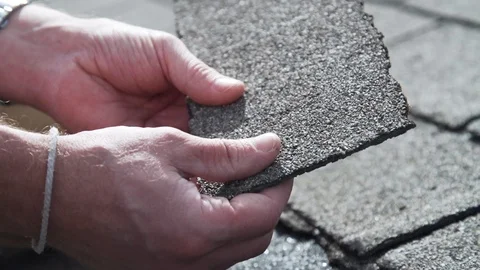 Roof inspector cracking old asphalt shingles during residential inspection Stock Footage