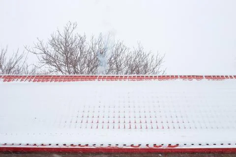 The roof made of metal tiles is covered with falling snow. Reliable roof in w Stock Photos