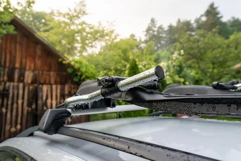 Roof rack for transporting bicycles by car mounted on a silver car. A wet c.. Stock Photos