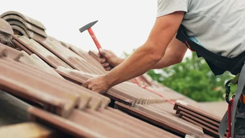 Roof worker using hammer and nails to put tiles into place, side view Stock Footage 203728409