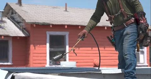 Roofer applying granulated APP Torch Down and Using a Roller Stock Footage 277973936
