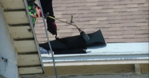 Roofer applying granulated APP Torch Down and Using a Roller Stock Footage 285389950