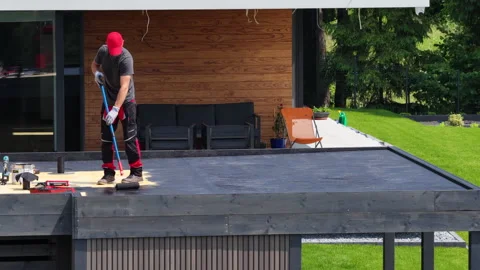 Roofer Applying Protective Layer to a Modern Flat Roof in Sunny Suburban Area Stock Footage 313536510