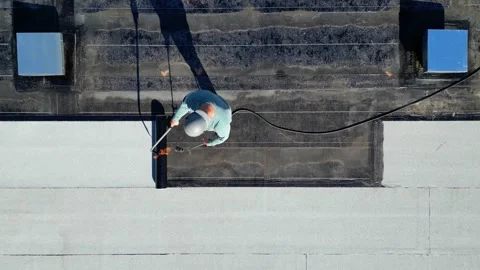 Roofer applying torch to bitumen membrane on torch down roof Stock Footage 317956815