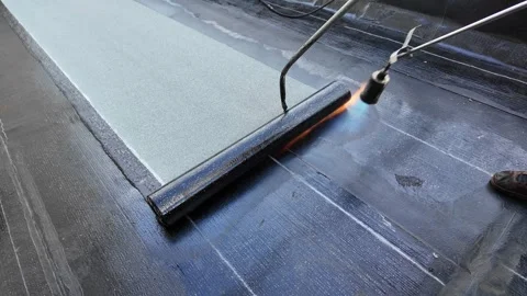 Roofer applying torch to bitumen membrane on torch down roof Stock Footage 317956891