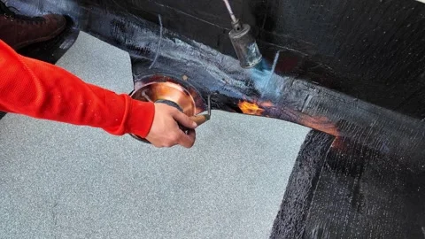 Roofer applying torch to bitumen membrane on torch down roof Stock Footage 317956930