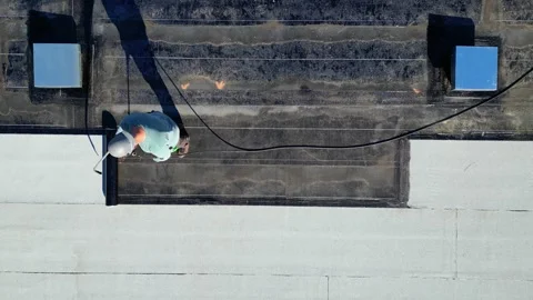 Roofer applying torch to bitumen membrane on torch down roof Stock Footage 317957064