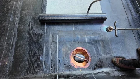 Roofer applying torch to bitumen membrane on torch down roof Stock Footage 317957280