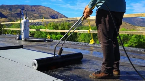 Roofer applying torch to bitumen membrane on torch down roof Video stock 317957350