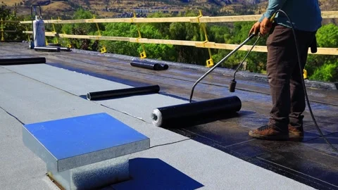 Roofer applying torch to bitumen membrane on torch down roof Stock Footage 317957378