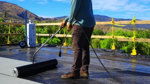 Roofer applying torch to bitumen membrane on torch down roof Stock Footage 317957421