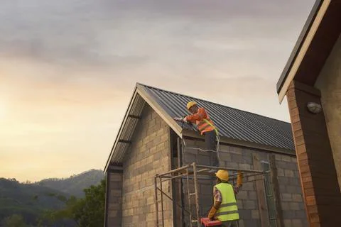 Roofer Construction worker install new roof,Roofing tools,Electric drill used Stock Photos