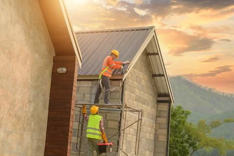 Roofer Construction worker install new roof,Roofing tools,Electric drill used Stock Photos