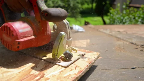 Roofer cutting a wooden board with a circular saw during roof construction and Stock Footage 346790535