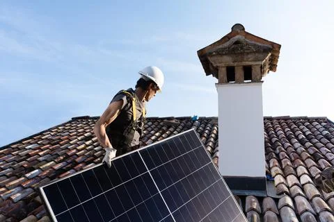 Roofer Installing Solar Panel on Residential Clay Tile Roof. Stock Photos